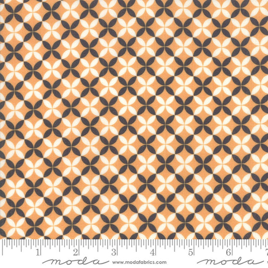 A close-up of a repeating geometric fabric pattern with peach, off-white, and dark gray shapes, shown with a ruler along the bottom edge for scale. The word 'moda' and website text appear at the bottom.