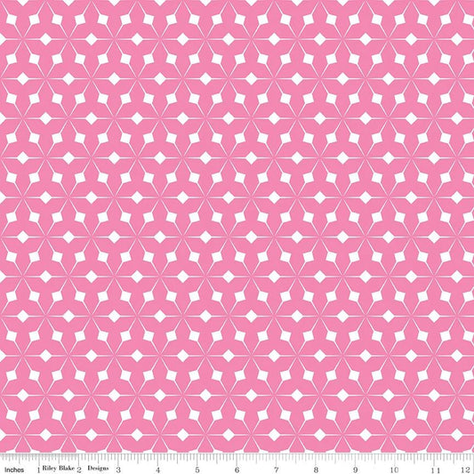 Pink and white geometric patterned fabric with a repeating starburst motif, shown flat with a ruler along the bottom edge for scale.