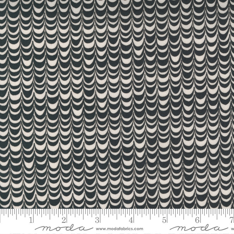 A close-up of a fabric pattern with repeating vertical rows of curved scallop or wave shapes in dark charcoal gray and warm off-white. A ruler strip is visible along the bottom edge with Modra branding and the website modrafabrics.