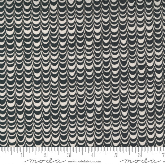 A close-up of a fabric pattern with repeating vertical rows of curved scallop or wave shapes in dark charcoal gray and warm off-white. A ruler strip is visible along the bottom edge with Modra branding and the website modrafabrics.