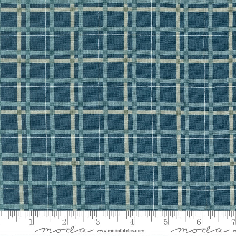 A close-up of a fabric pattern featuring a blue and teal plaid grid with thin cream intersecting lines, with a white ruler at the bottom showing measurements. The brand name 'moda' is visible on the ruler.