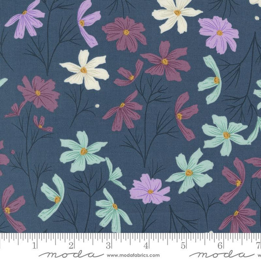 A close-up of a fabric pattern featuring stylized flowers in purple, white, and mint green with dark pink centers and black stems on a dark blue-gray background. A ruler scale and the Modafabrics logo are visible along the bottom edge.