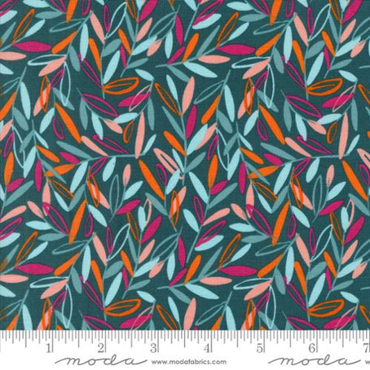 A close-up of a fabric pattern featuring a dense, repeating leaf design in orange, pink, light blue, and white on a dark teal background, with a white ruler at the bottom showing the scale.