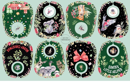 Eight Christmas-themed bibs arranged in a 2x4 grid on a pale mint background. The bibs feature dark green and black backgrounds with floral borders, holiday illustrations, and festive text including 'Merry Christmas' and 'Santa's Little Helper'.