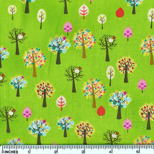 Bright green fabric with a repeating pattern of stylized trees in multiple colors, including pink, red, blue, yellow, and white, with a 12-inch ruler along the bottom edge for scale.