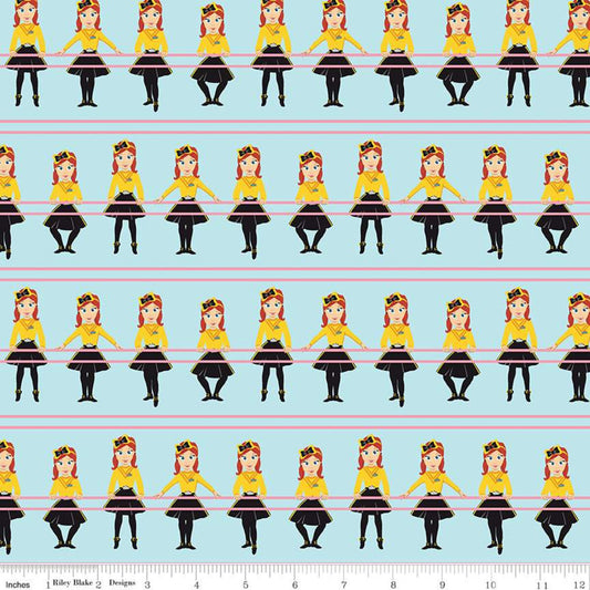 A repeating fabric pattern featuring cartoon girls in yellow tops, black skirts, and red hair on a light blue background, with a ruler strip at the bottom showing scale.