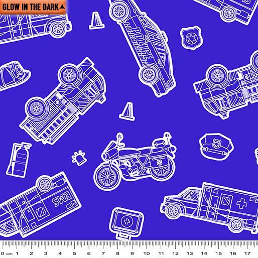 A repeating pattern of white outline emergency vehicle illustrations on a bright blue background, including police cars, an ambulance, a motorcycle, a first-aid kit, a helmet, a cone, and a paw print. A small orange label in the top left reads 'GLOW IN THE DARK' and a ruler scale appears along the bottom edge.
