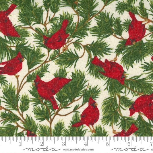 A close-up of a fabric pattern featuring red cardinals perched on green pine branches over an off-white background, with a ruler along the bottom edge showing scale. The brand name 'Moda' is printed at the bottom.