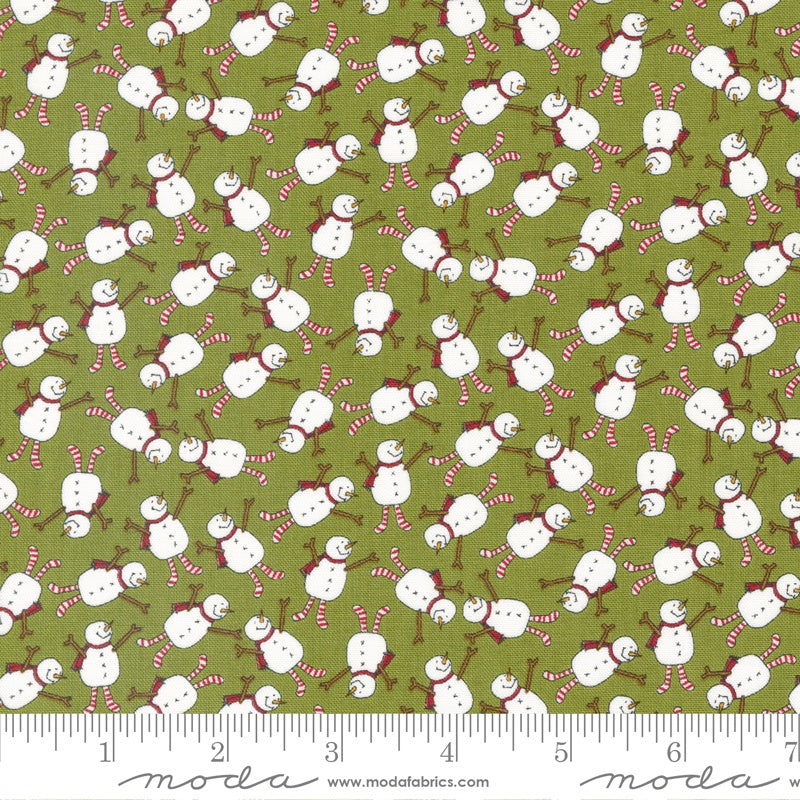 A repeating fabric pattern featuring white snowmen with red and white striped scarves and poles on an olive green background, with a measuring ruler along the bottom edge showing scale.