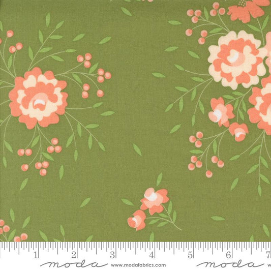 Green fabric with a floral print featuring coral-pink and cream flowers, green leaves, and small pink berry clusters. A white ruler is visible along the bottom edge showing measurement markings, and the brand name 'moda' appears at the bottom.