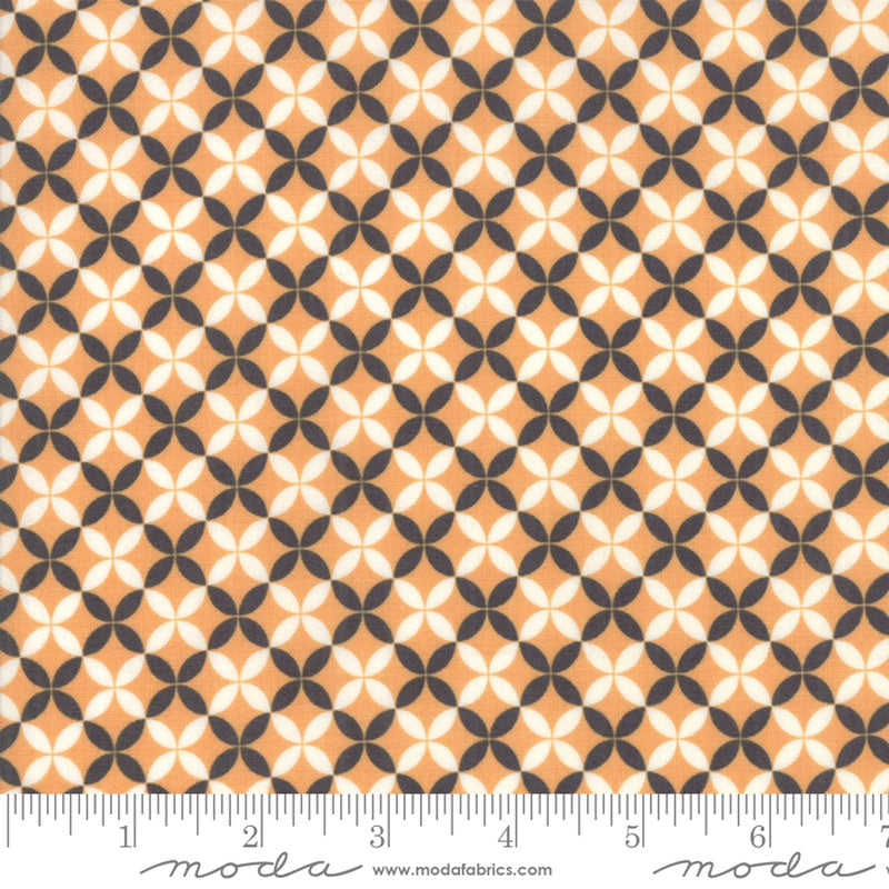 A close-up of a repeating geometric fabric pattern with peach, off-white, and dark gray shapes, shown with a ruler along the bottom edge for scale. The word 'moda' and website text appear at the bottom.