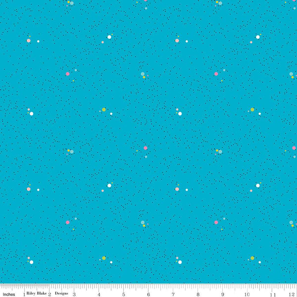 A repeating fabric pattern on a bright turquoise blue background with tiny scattered dots and small floral motifs in pink, yellow, green, and white. A white ruler along the bottom edge shows measurements in inches and includes the text 'Riley Blake Designs'.