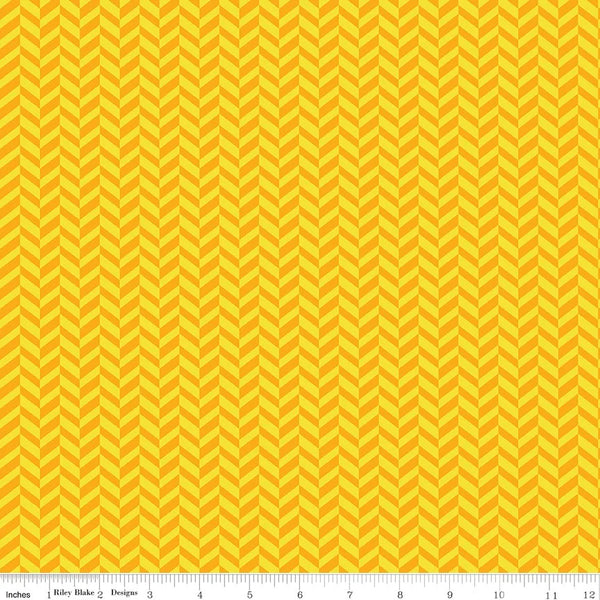 A close-up of a fabric pattern featuring a repeating yellow and orange chevron design, with a measuring ruler visible along the bottom edge.