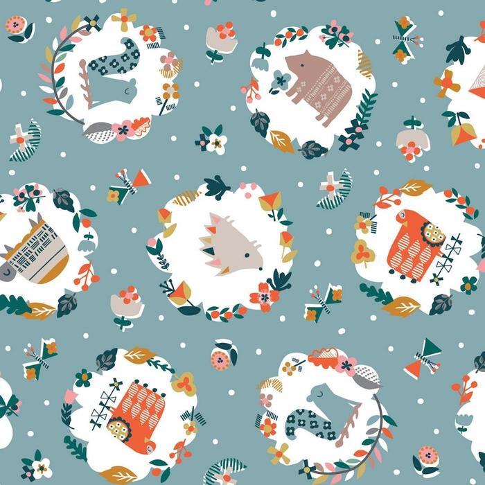 A repeating seamless fabric pattern featuring whimsical woodland animal illustrations inside white oval frames, surrounded by floral wreaths and small decorative motifs on a dusty blue background with white polka dots.