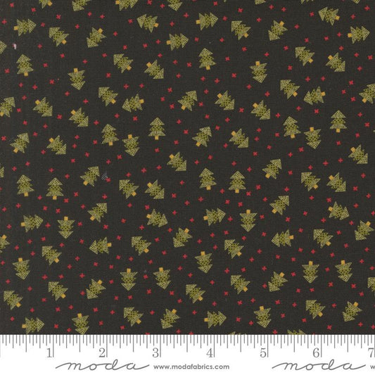 Black fabric with a repeating pattern of small gold Christmas trees and red dots, shown flat with a white ruler along the bottom edge for scale. The word 'moda' and website text appear at the bottom.
