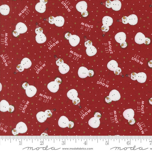 Red fabric with a repeating pattern of white snowmen, white text reading 'LET IT SNOW' , small white dots, and scattered gold stars, shown with an inch ruler along the bottom edge.