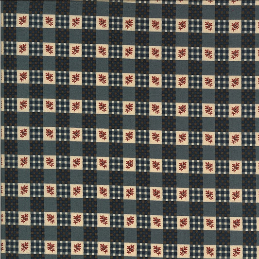 A close-up of a fabric pattern featuring a checkered grid of navy blue, slate blue, beige, and white squares, with small red floral motifs in the center of the beige squares.