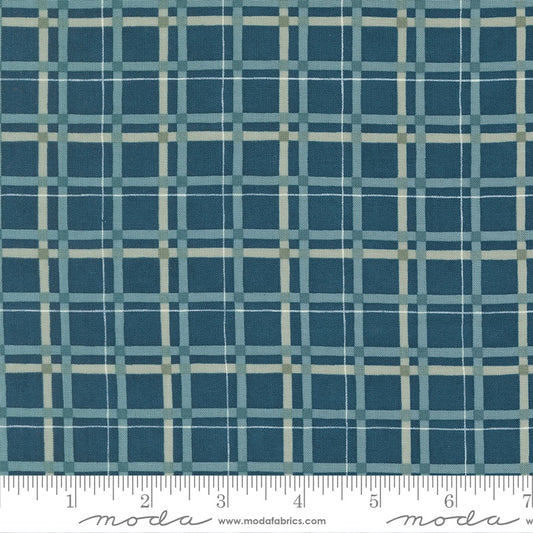 A close-up of a fabric pattern featuring a blue and teal plaid grid with thin cream intersecting lines, with a white ruler at the bottom showing measurements. The brand name 'moda' is visible on the ruler.