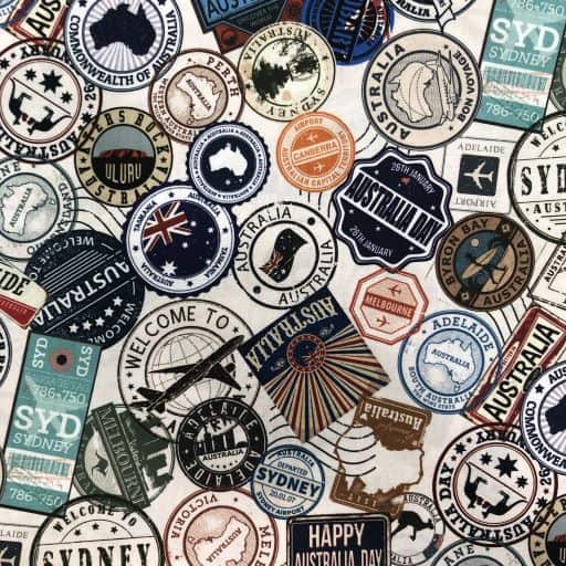 A close-up of a fabric pattern featuring numerous vintage-style Australian travel stamps and postcards in various colours like blue, orange, green, and black on a white background.