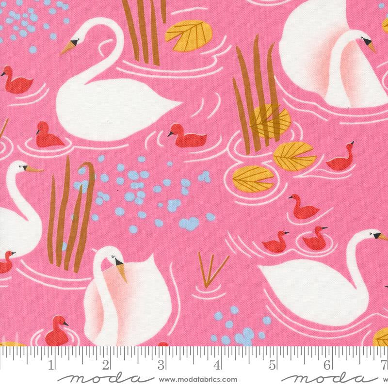 Pink fabric with a repeating pattern of white swans, red ducks, yellow lily pads, and blue water splashes, shown with a ruler at the bottom indicating scale. The brand name 'moda fabrics' is printed along the bottom edge.