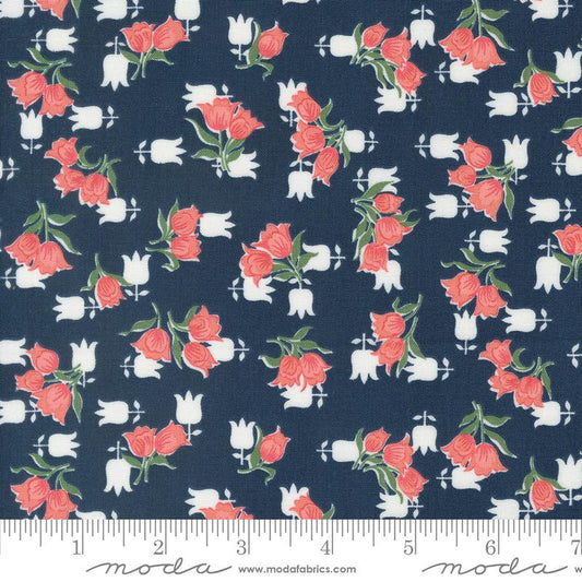 A close-up of a fabric pattern featuring coral pink roses and white tulips on a dark navy blue background, with a ruler at the bottom showing the scale.
