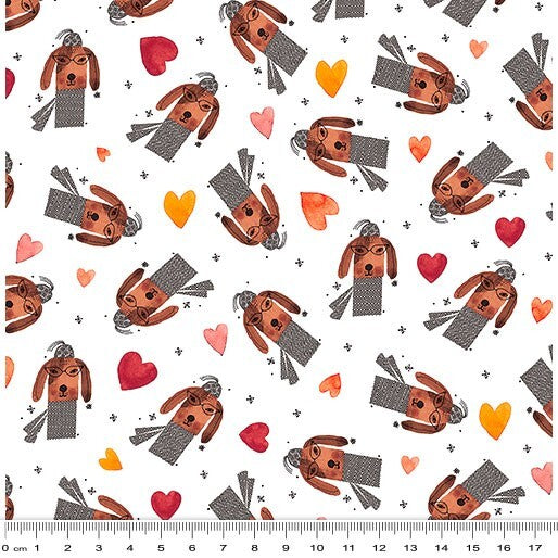 A repeating fabric pattern featuring cartoon dachshund dogs wearing gray sweaters, scattered red and orange hearts, and small gray crosses on a white background, with a ruler at the bottom showing scale.