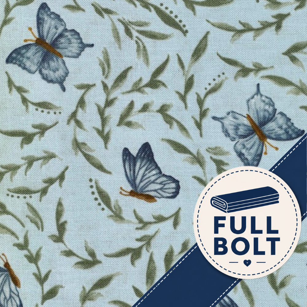 A close-up of a fabric pattern featuring blue butterflies and olive green leaves on a pale blue background, with a white ruler along the left edge showing measurements.