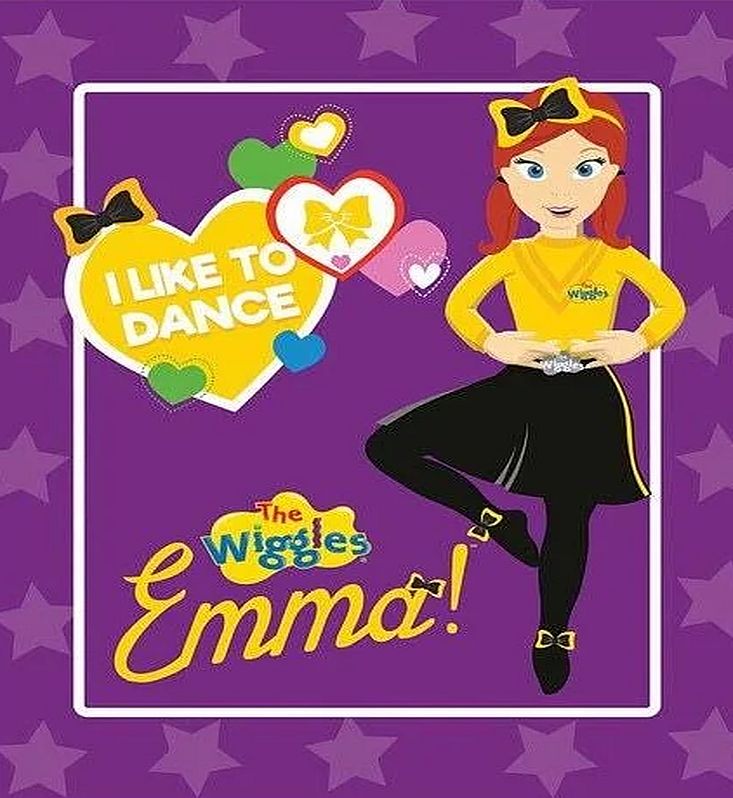 The Wiggles Emma fabric panel featuring a cartoon illustration of Emma in her signature yellow top and black skirt against a purple star background, with the text 'I LIKE TO DANCE' and 'The Wiggles Emma!'.