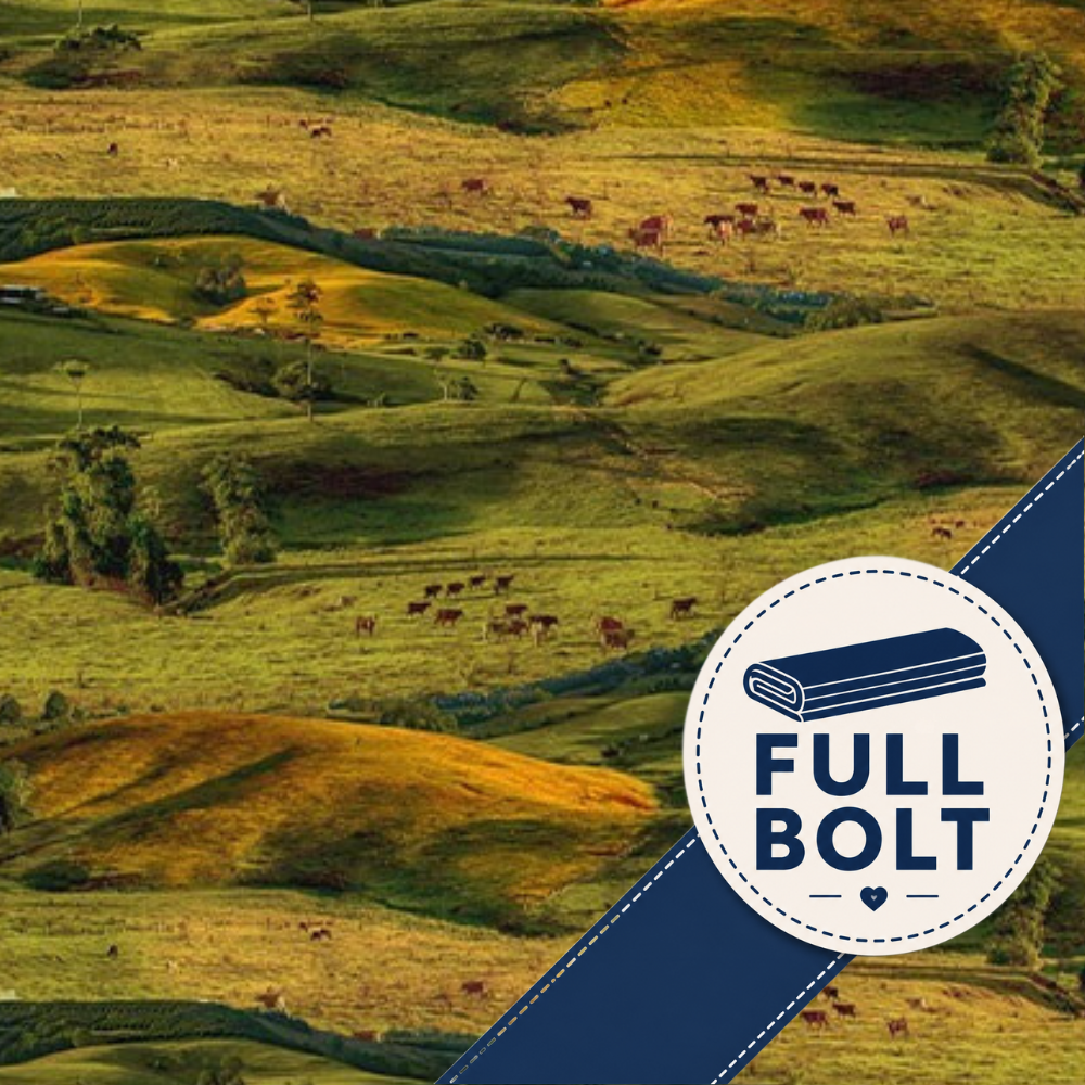 A scenic fabric landscape of rolling green and golden hills with small cows grazing, overlaid with a dark blue diagonal banner and a circular white badge reading FULL BOLT with an icon of folded material.