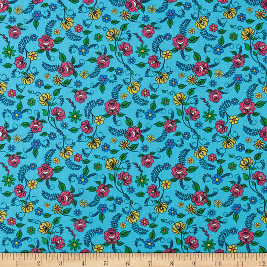 A close-up of a fabric pattern featuring a turquoise blue background with a dense, repeating floral print of pink, yellow, and blue flowers with green leaves and vines. A wooden ruler is visible along the bottom edge to show scale.