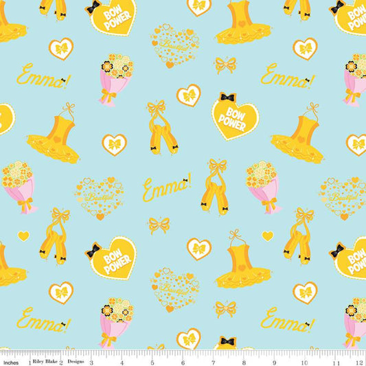 A repeating fabric pattern on a light blue background featuring yellow high heels, yellow bows, yellow hearts, pink flower bouquets, and the words 'Emma!' and 'BOW POWER!'. A white ruler strip is visible along the bottom edge.