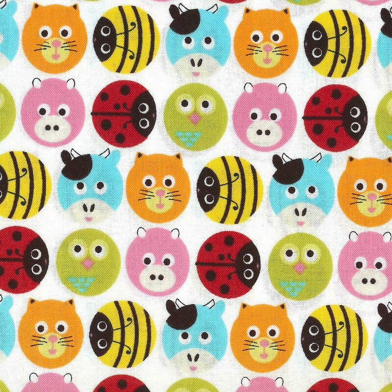 A close-up of a white fabric with a colorful repeating pattern of cartoon animal faces, including orange cats, yellow and black striped bees, light blue cats, red ladybugs, pink pigs